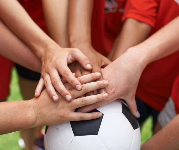 Team vereinigt Hände auf Fußball