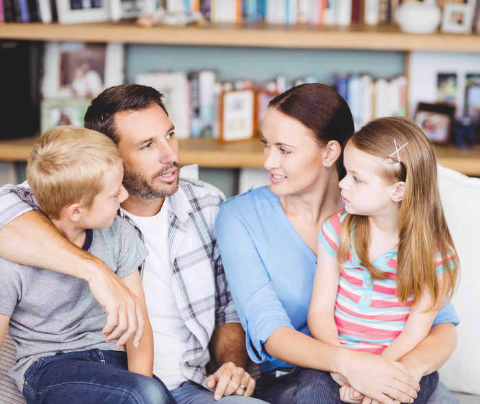 Vierköpfige Familie sitzt auf dem Sofa und redet Vierköpfige Familie sitzt auf dem Sofa und redet