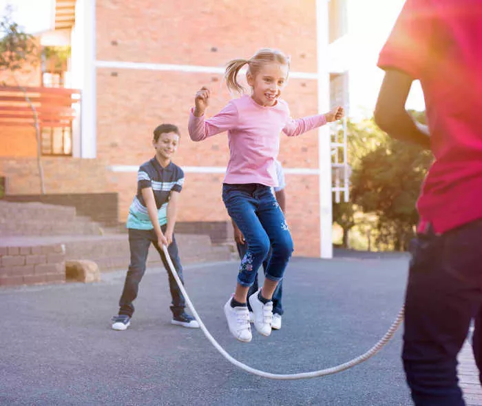 Kinder spielen auf dem Schulhof Seilspringen