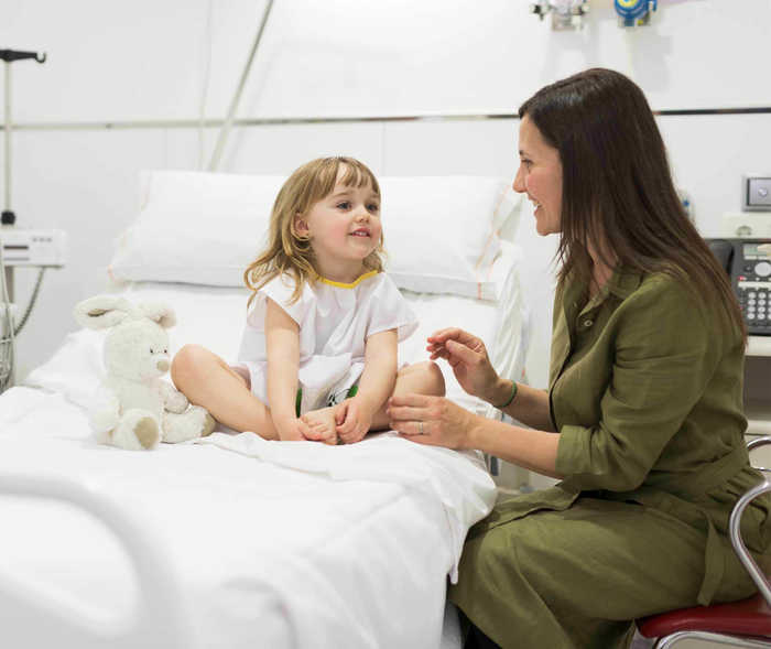 Mutter redet mit ihrer Tochter die auf dem Krankenbett sitzt