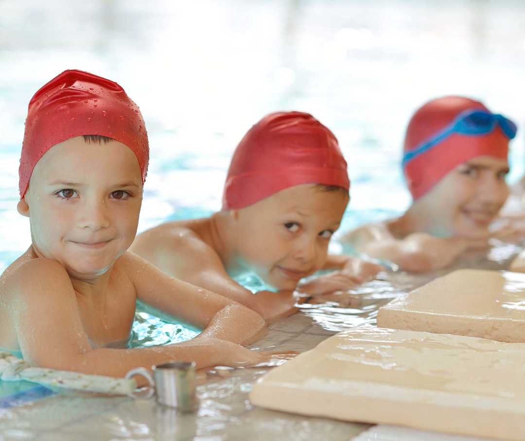 Kinder am Schwimmbeckenrand lächeln in die Kamera Kinder am Schwimmbeckenrand lächeln in die Kamera