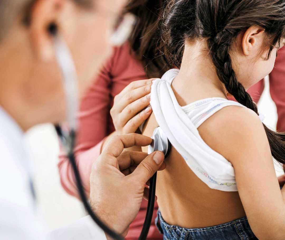 Rücken eines jungen Mädchen wird mit Stethoskop abgehört