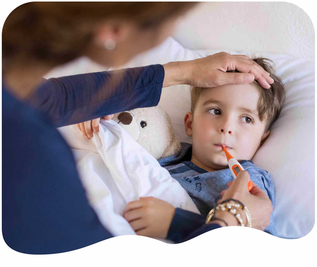 Junge liegt im Bett mit einem Fieberthermometer im Mund