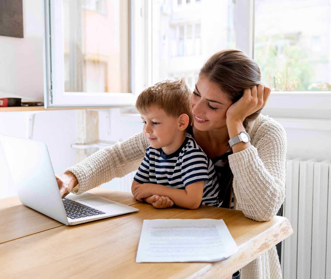 Mutter hat ihren Sohn auf dem Schoß und sie schauen auf einen Laptop