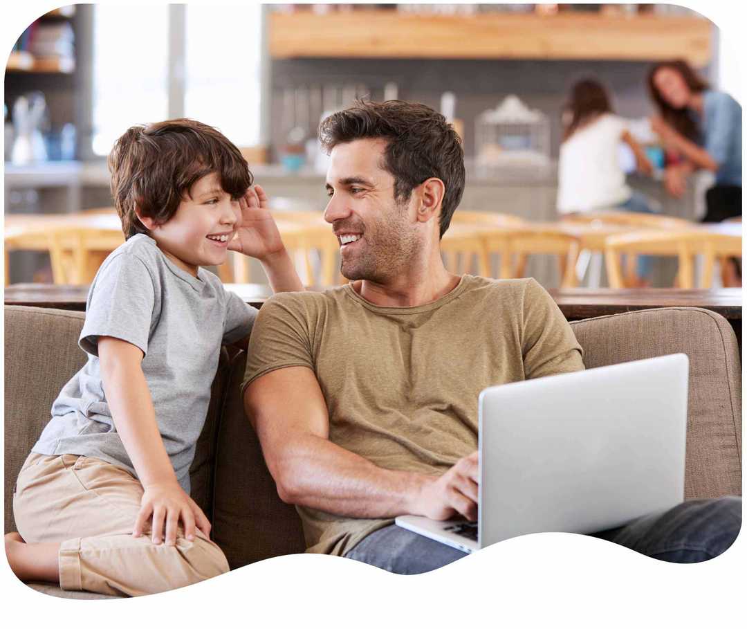 Vater lacht mit seinem Sohn vor einem Laptop Vater lacht mit seinem Sohn vor einem Laptop