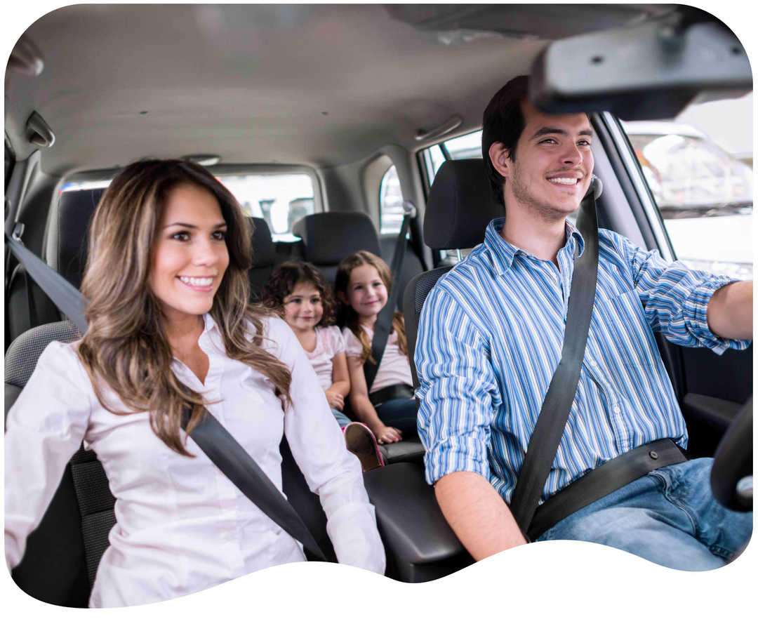 Vierköpfige Familie sitzt im Auto und lacht