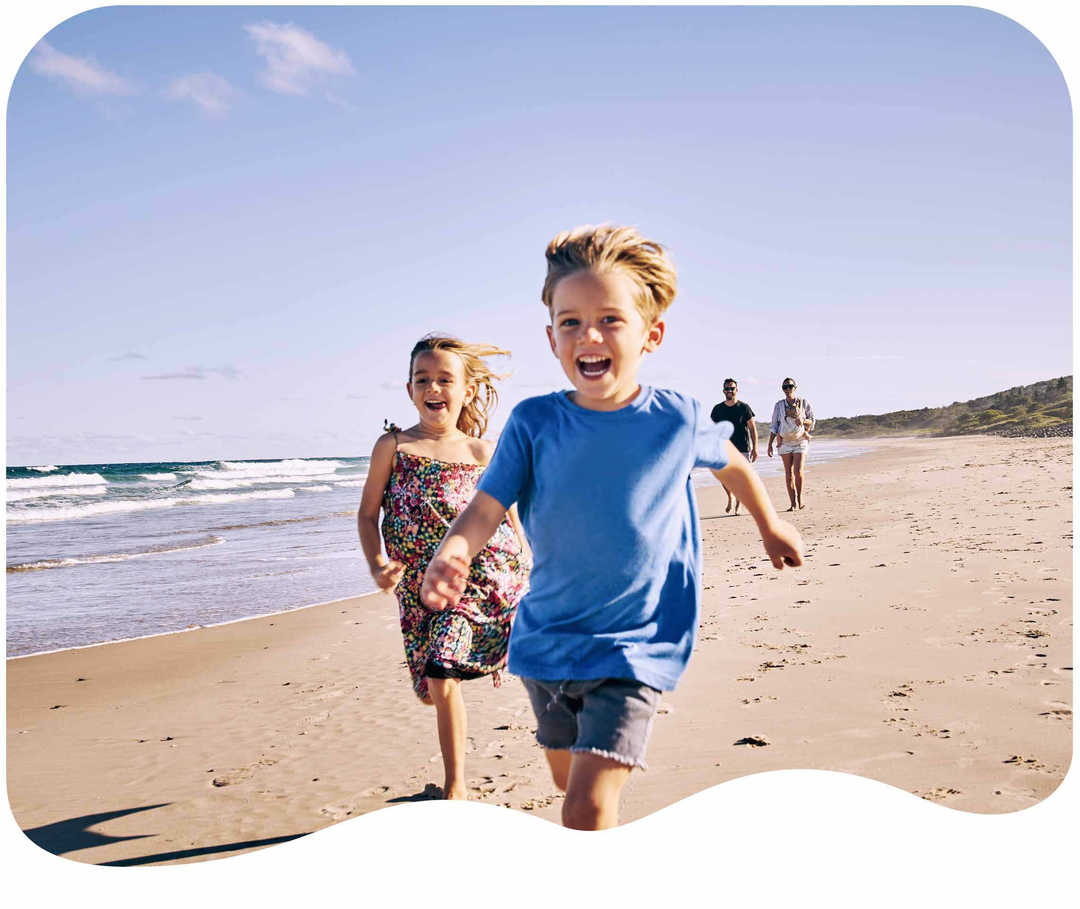 Kinder laufen lachend am Strand entlang