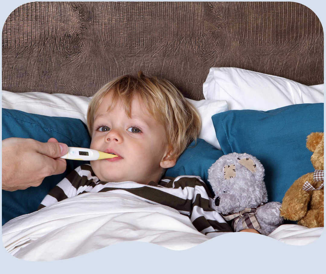 Ein Junge im Bett mit Fieberthermometer im Mund