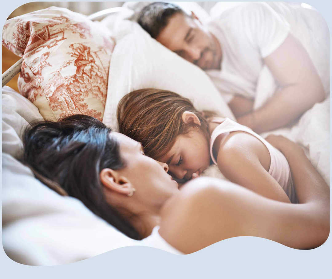 Eltern kuscheln mit ihrer Tochter im Bett