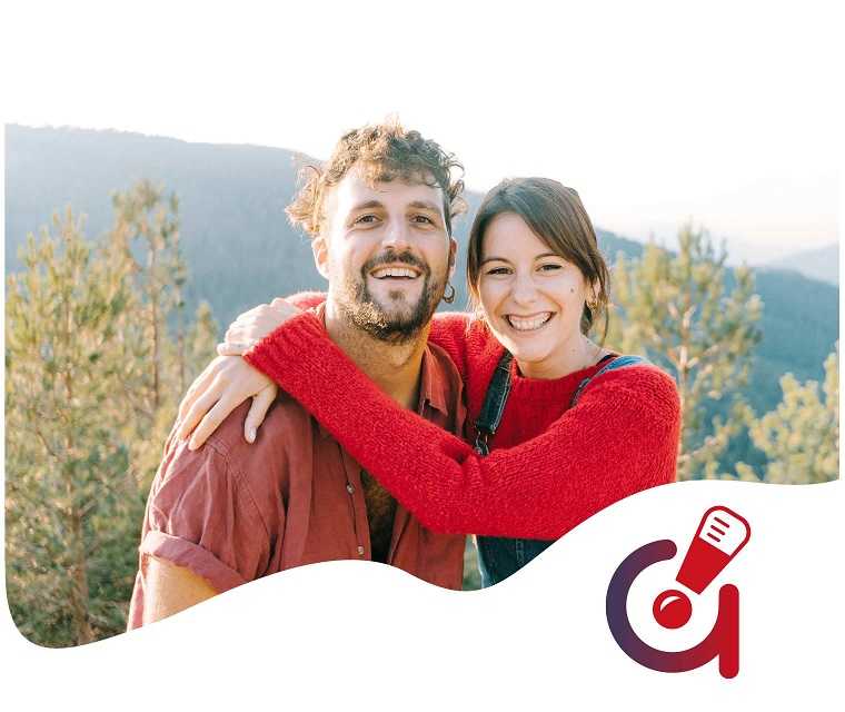 Ein junges Paar umarmt sich und lächelt in die Kamera